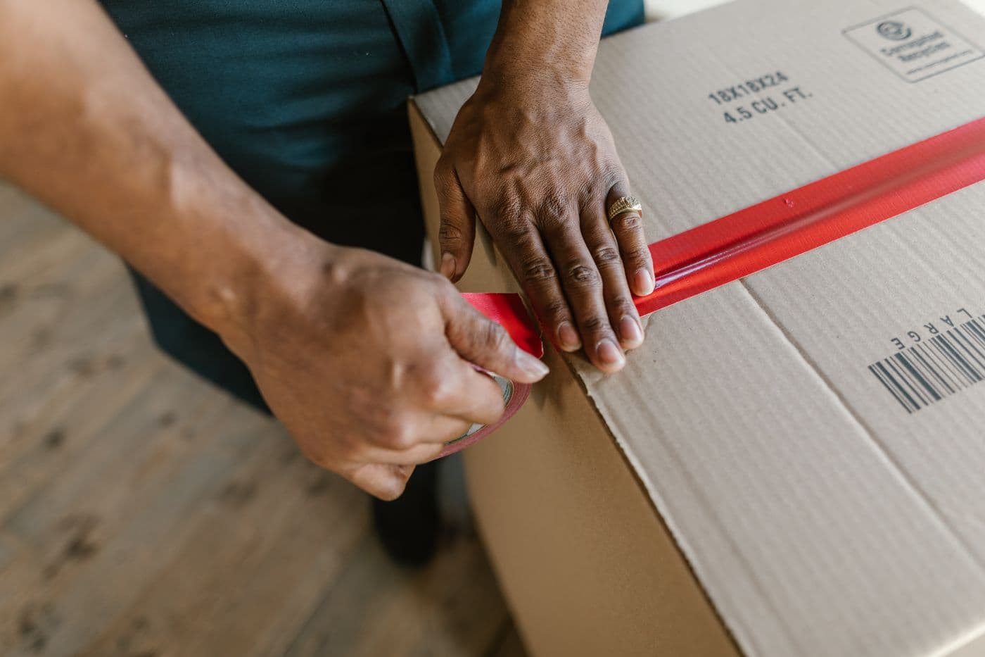 Hands sealing a plain cardboard parcel